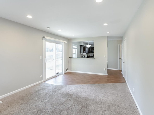 unfurnished living room with recessed lighting, carpet, and baseboards