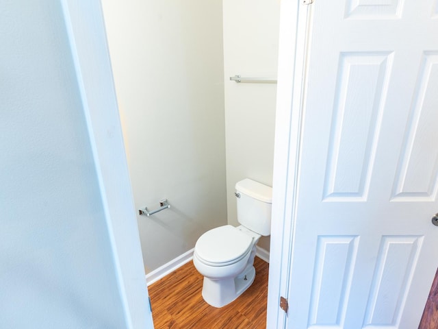 bathroom featuring toilet, wood finished floors, and baseboards