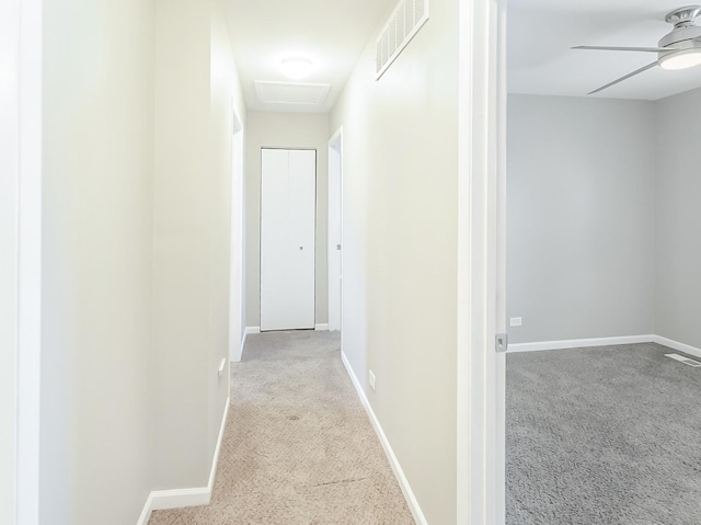 corridor with attic access, carpet, visible vents, and baseboards