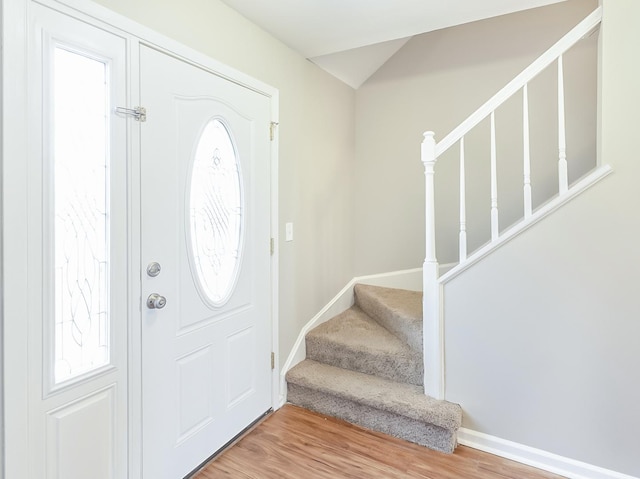 foyer featuring baseboards, wood finished floors, and stairs