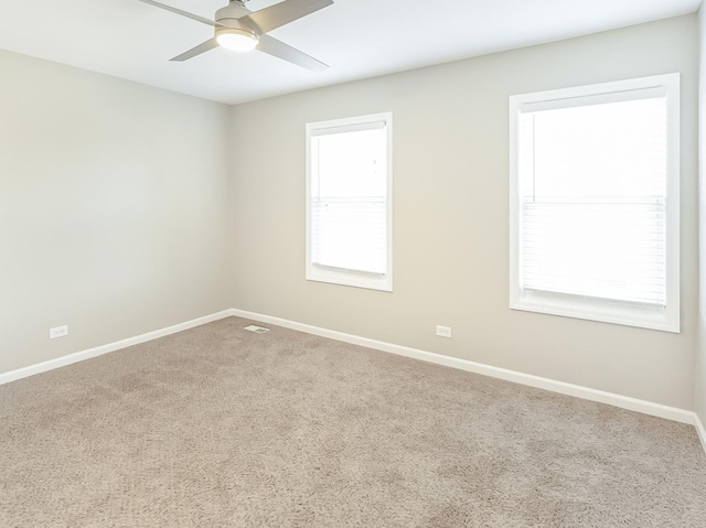 unfurnished room with visible vents, baseboards, carpet, and a ceiling fan