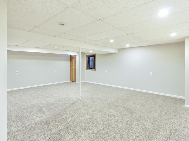 finished basement featuring a drop ceiling, recessed lighting, baseboards, and carpet