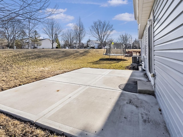 view of yard featuring cooling unit, a trampoline, and a patio area