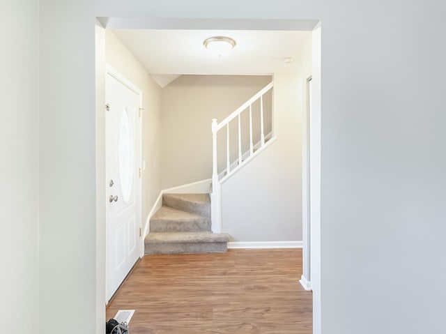 hallway with stairway, baseboards, and wood finished floors