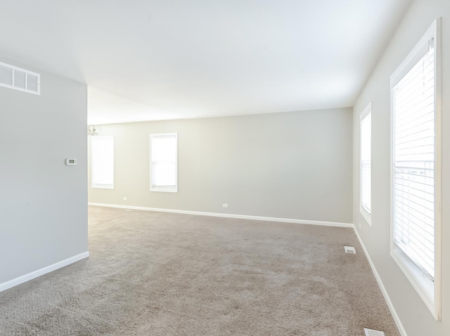 carpeted spare room with visible vents and baseboards