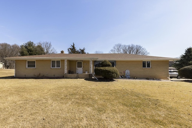 ranch-style home with brick siding, a chimney, and a front lawn