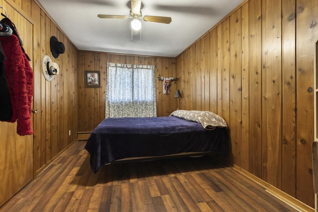 bedroom featuring wood walls, a baseboard radiator, a ceiling fan, and wood finished floors