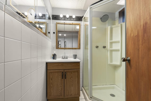 full bathroom with vanity, tile walls, a stall shower, and a textured ceiling