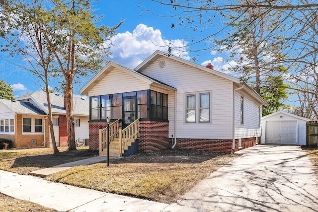 bungalow-style home with concrete driveway, a detached garage, an outdoor structure, and a sunroom