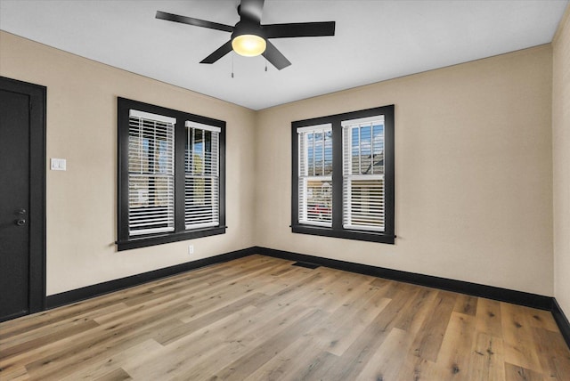 spare room with visible vents, light wood-style flooring, baseboards, and ceiling fan