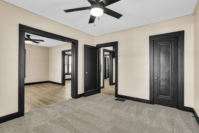 carpeted empty room featuring visible vents, baseboards, and ceiling fan