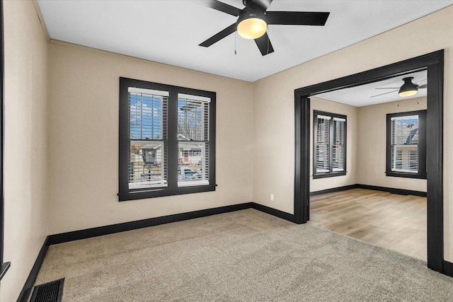 spare room with carpet flooring, visible vents, baseboards, and a ceiling fan