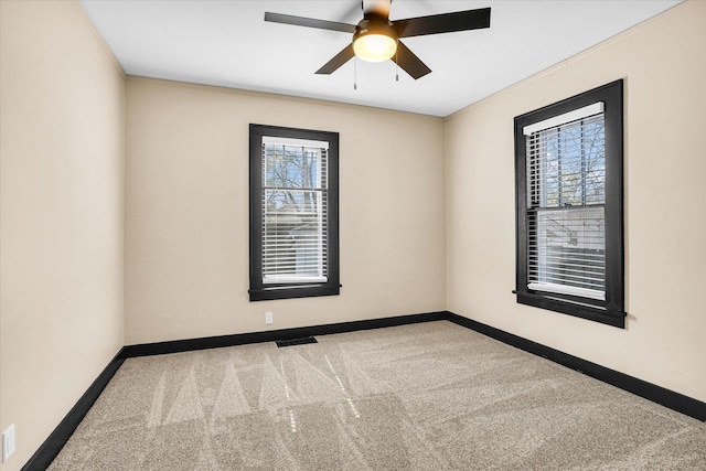 carpeted spare room with visible vents, baseboards, and ceiling fan