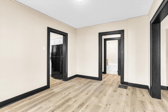 unfurnished room with light wood finished floors, visible vents, and baseboards