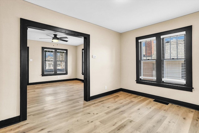 spare room featuring light wood finished floors, a healthy amount of sunlight, and baseboards