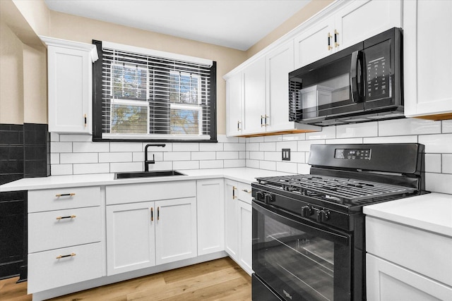 kitchen featuring a sink, white cabinetry, black appliances, and light countertops