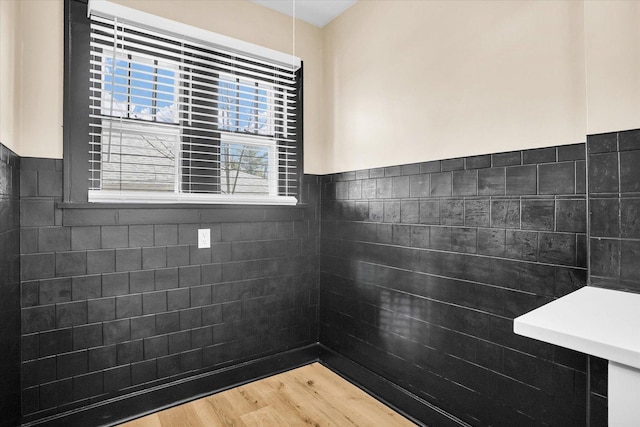 bathroom with tile walls, wood finished floors, and wainscoting