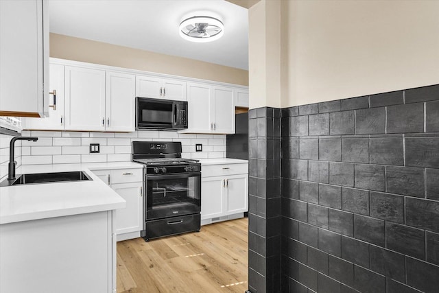 kitchen featuring white cabinetry, black appliances, light countertops, and a sink