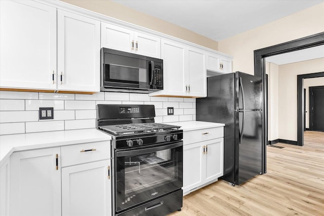 kitchen featuring tasteful backsplash, white cabinets, black appliances, and light countertops