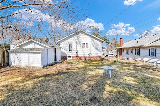 back of house featuring a yard, an outbuilding, and fence