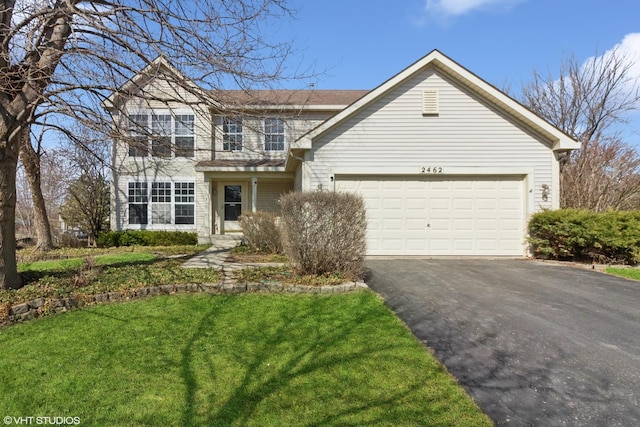 traditional-style home featuring a front lawn, an attached garage, and driveway