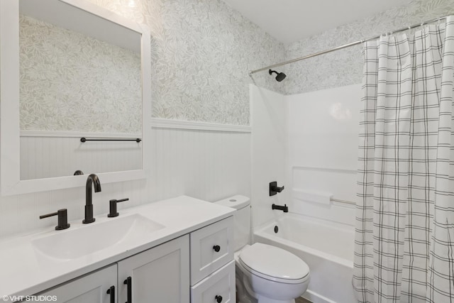 bathroom featuring vanity, a wainscoted wall, wallpapered walls, shower / bath combo, and toilet