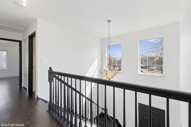 hall with a chandelier, an upstairs landing, baseboards, and dark wood finished floors