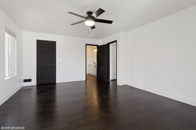 spare room with a wealth of natural light, visible vents, a ceiling fan, dark wood-style floors, and baseboards