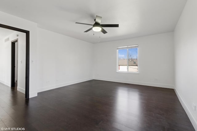 spare room with dark wood finished floors, visible vents, baseboards, and ceiling fan