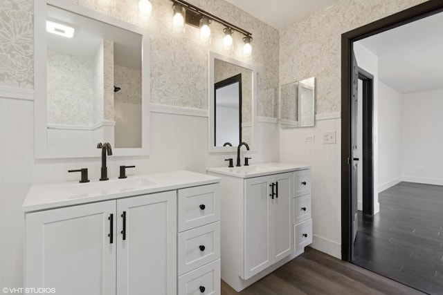 full bath featuring a wainscoted wall, wallpapered walls, wood finished floors, and a sink