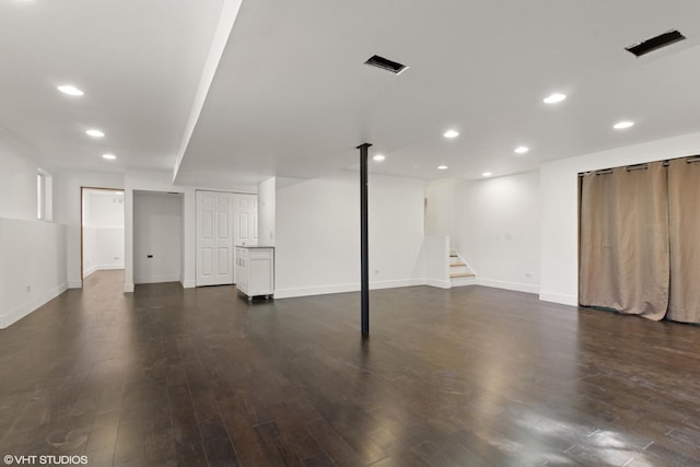 finished below grade area featuring recessed lighting, stairway, baseboards, and dark wood finished floors