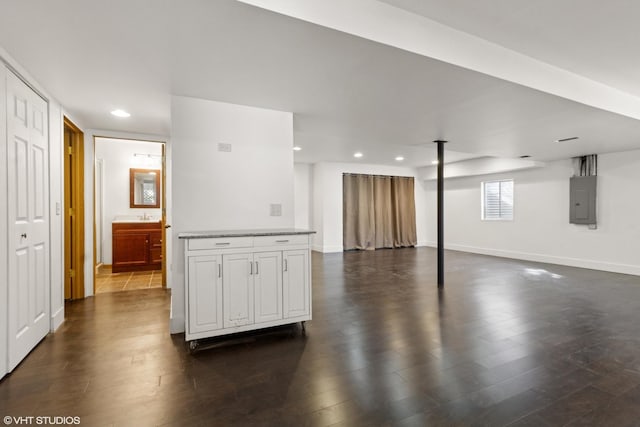 below grade area featuring electric panel, a sink, dark wood-style floors, recessed lighting, and baseboards