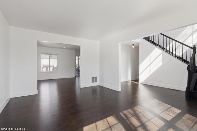 unfurnished living room featuring visible vents, baseboards, wood finished floors, and stairs