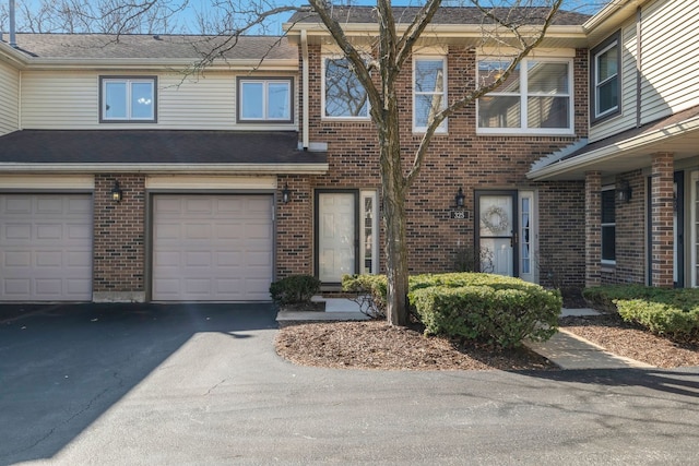 townhome / multi-family property featuring aphalt driveway, brick siding, a garage, and a shingled roof