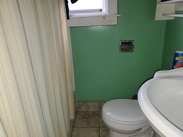 bathroom with tile patterned flooring, toilet, and a sink