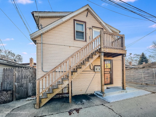 rear view of house featuring stairway and fence