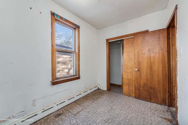 unfurnished bedroom featuring a baseboard heating unit and a closet