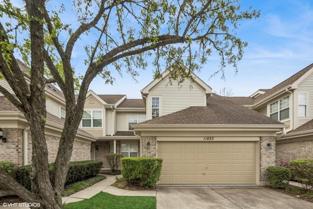 view of property with an attached garage, a shingled roof, brick siding, and concrete driveway
