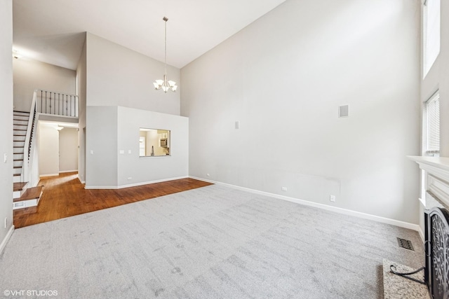 unfurnished living room with stairway, carpet floors, baseboards, a chandelier, and high vaulted ceiling