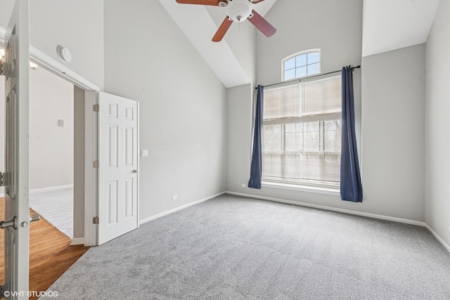 interior space featuring baseboards, carpet, high vaulted ceiling, and ceiling fan