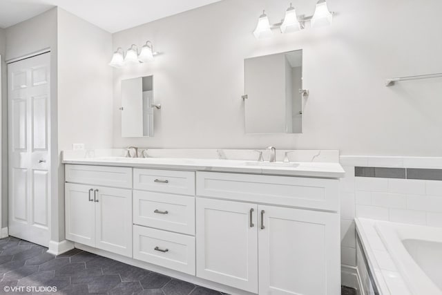 full bathroom with tiled tub, tile patterned floors, a sink, and double vanity