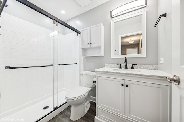 full bathroom with a shower stall, toilet, vanity, and wood finished floors