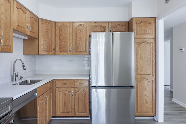 kitchen with decorative backsplash, light countertops, appliances with stainless steel finishes, and a sink