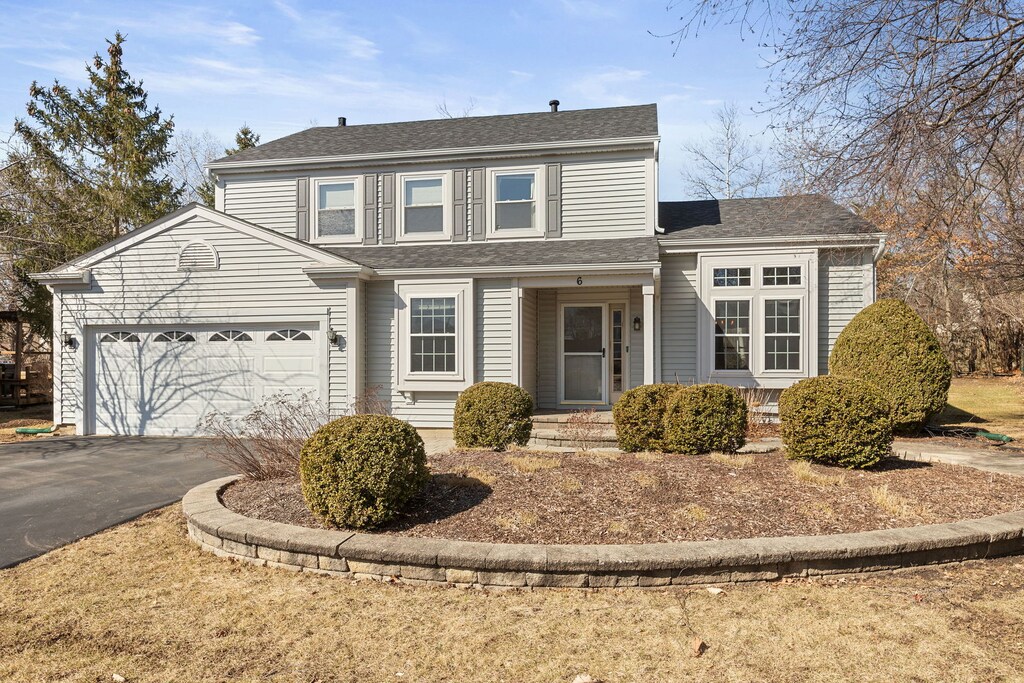 traditional-style home featuring aphalt driveway, a garage, and a shingled roof