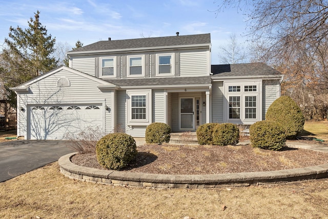 traditional-style home featuring aphalt driveway, a garage, and a shingled roof