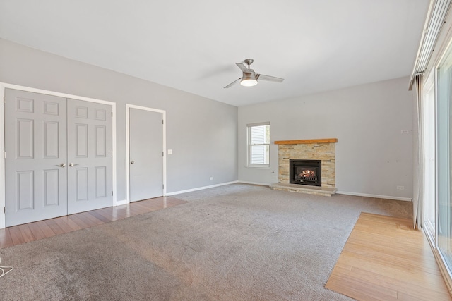 unfurnished living room with baseboards, carpet floors, ceiling fan, and a fireplace