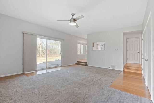 unfurnished living room featuring wood finished floors, a ceiling fan, visible vents, and baseboards