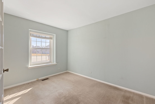 spare room featuring light carpet and baseboards