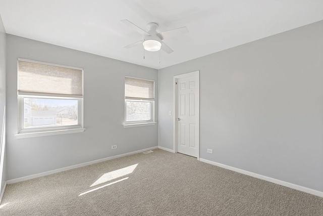 spare room featuring visible vents, light colored carpet, baseboards, and a ceiling fan