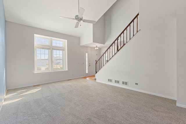 unfurnished living room featuring stairway, a ceiling fan, visible vents, high vaulted ceiling, and carpet flooring